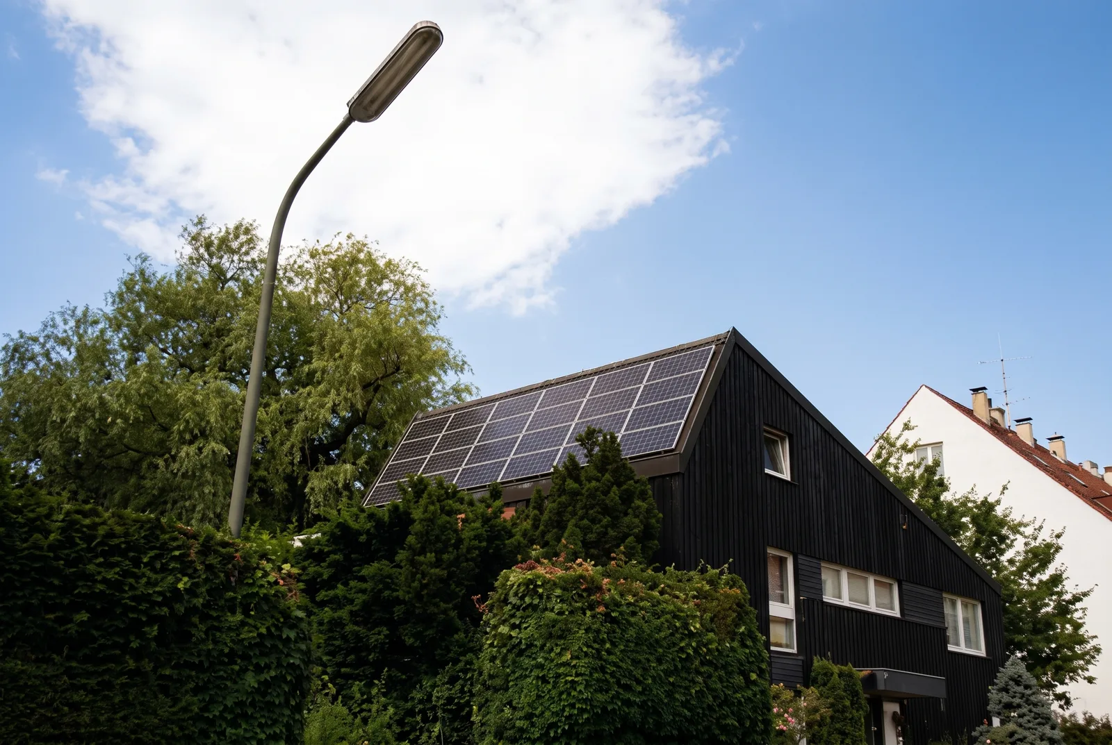 House with solar modules on the lower roof among trees