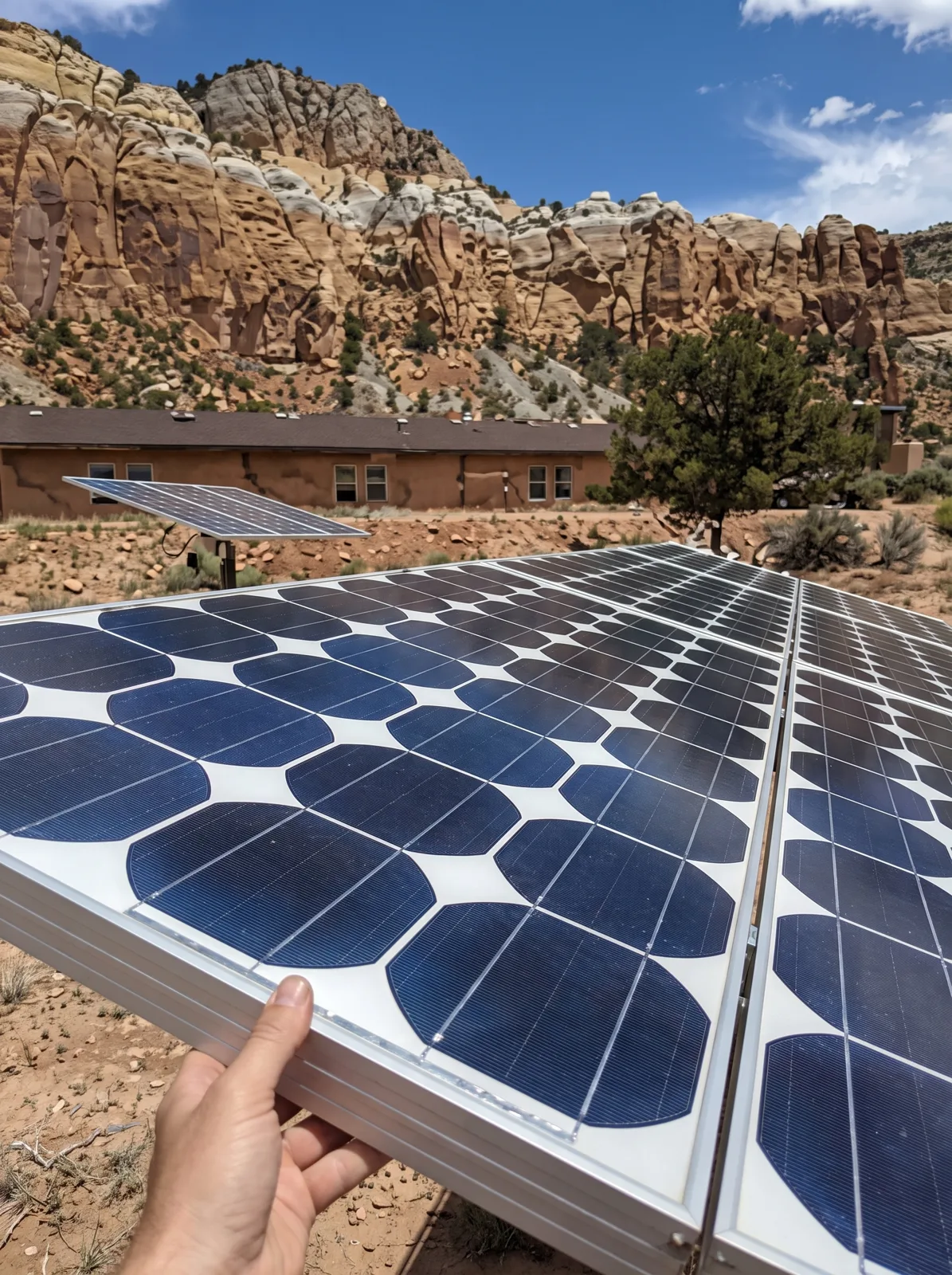 Hand holding a framed solar module with visible cells