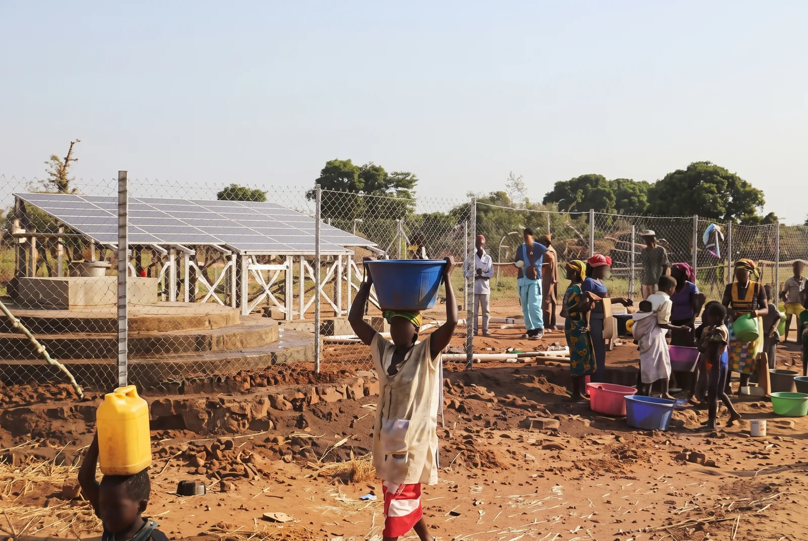 Village water point with a small solar array and people collecting water
